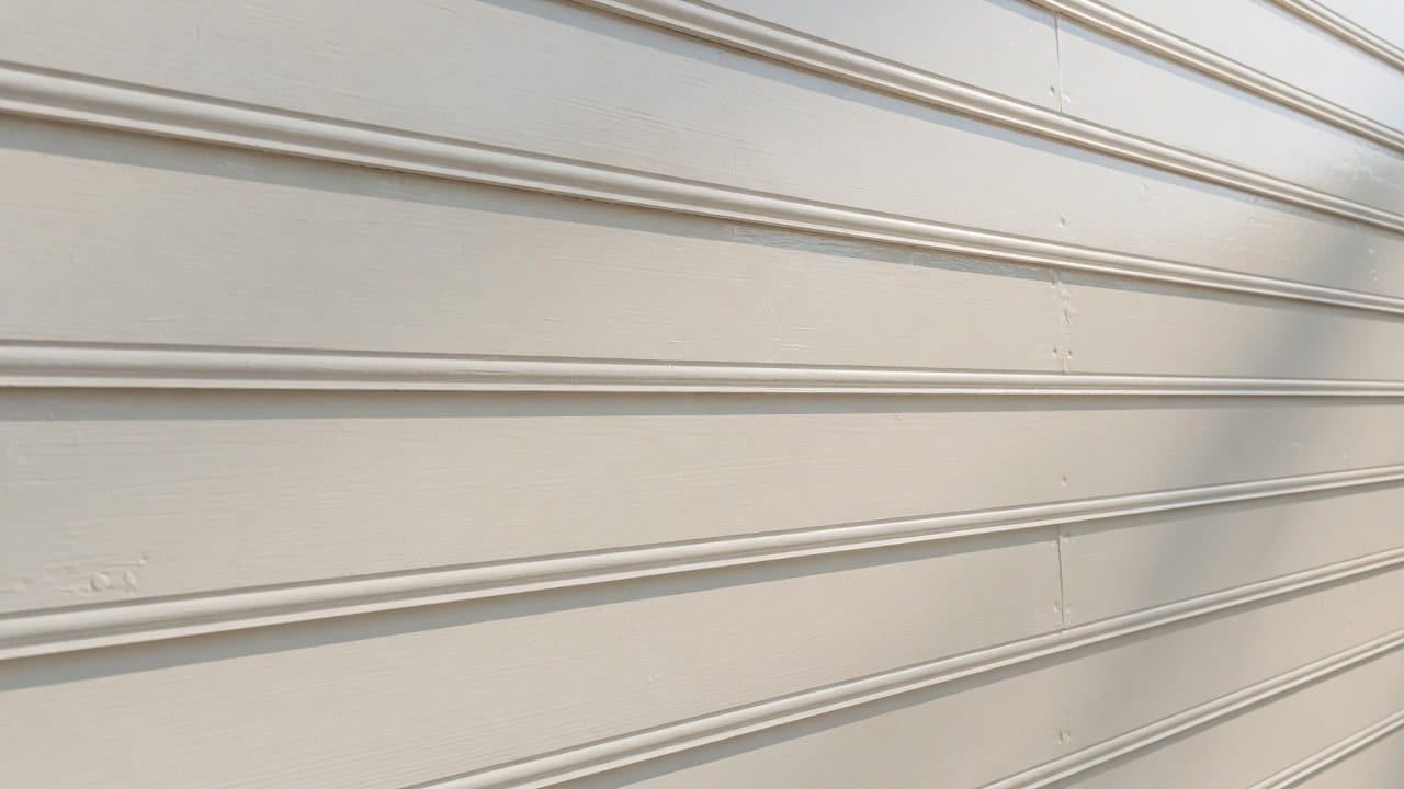Close-up of smooth freshly painted cedar clapboard with clean caulk lines on a New England home